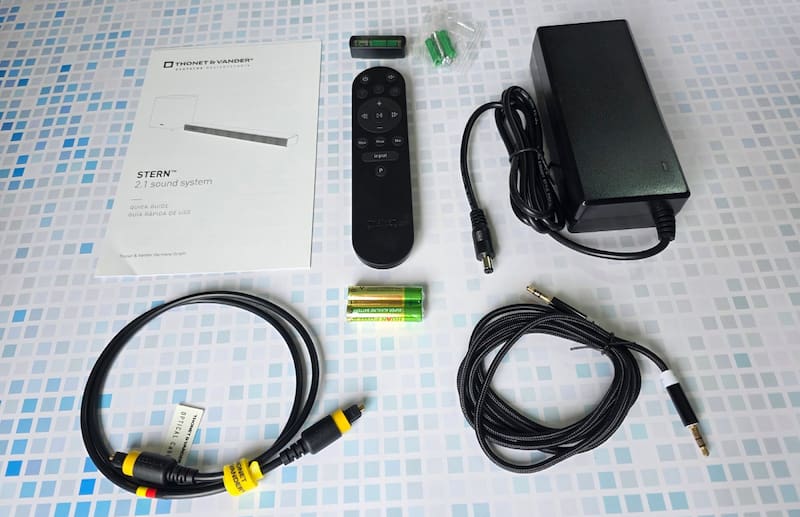 Los accesorios que trae la Stern. Trae cable óptico y analógico de 3,5 mm, control remoto con pilas, fuente de alimentación y un kit para montaje con nivel y tarugos.