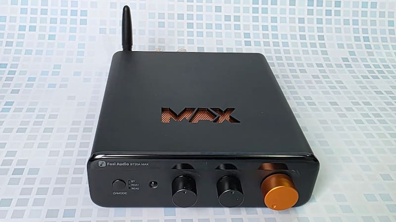 El frente tiene el botón de encendido/selección de entrada, LED indicador de entrada, perillas de graves y agudos, y control de volumen motorizado.