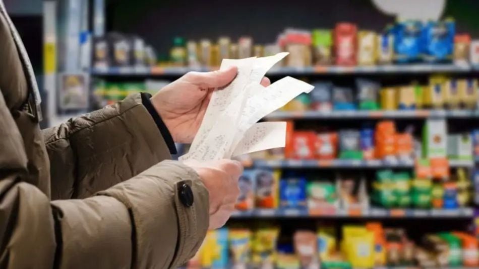Gráfico de inflación mensual con flecha descendente y góndola de supermercado