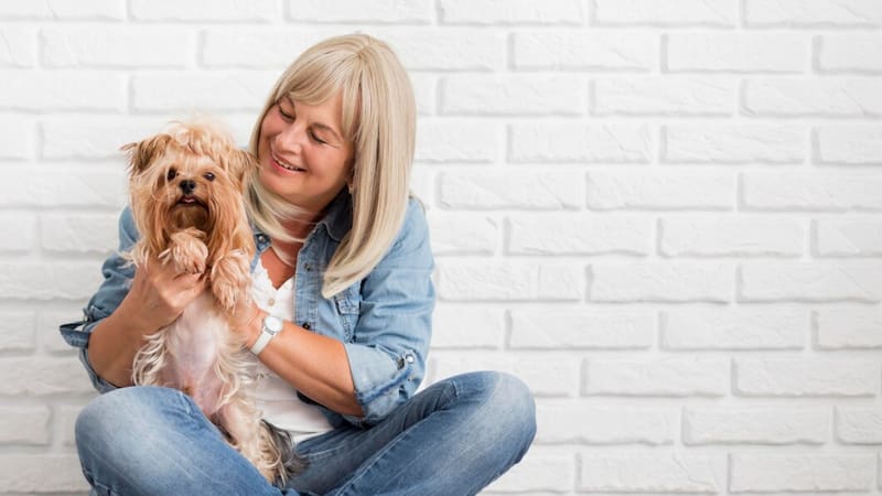 Mujer adulta con un perro en sus brazos. Foto: Freepik.es.