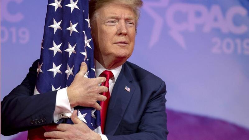 WASHINGTON, DC - MARCH 02: (AFP OUT) U.S. President Donald Trump hugs the U.S. flag during CPAC 2019 on March 02, 2019 in Washington, DC. The American Conservative Union hosts the annual Conservative Political Action Conference to discuss conservative ag