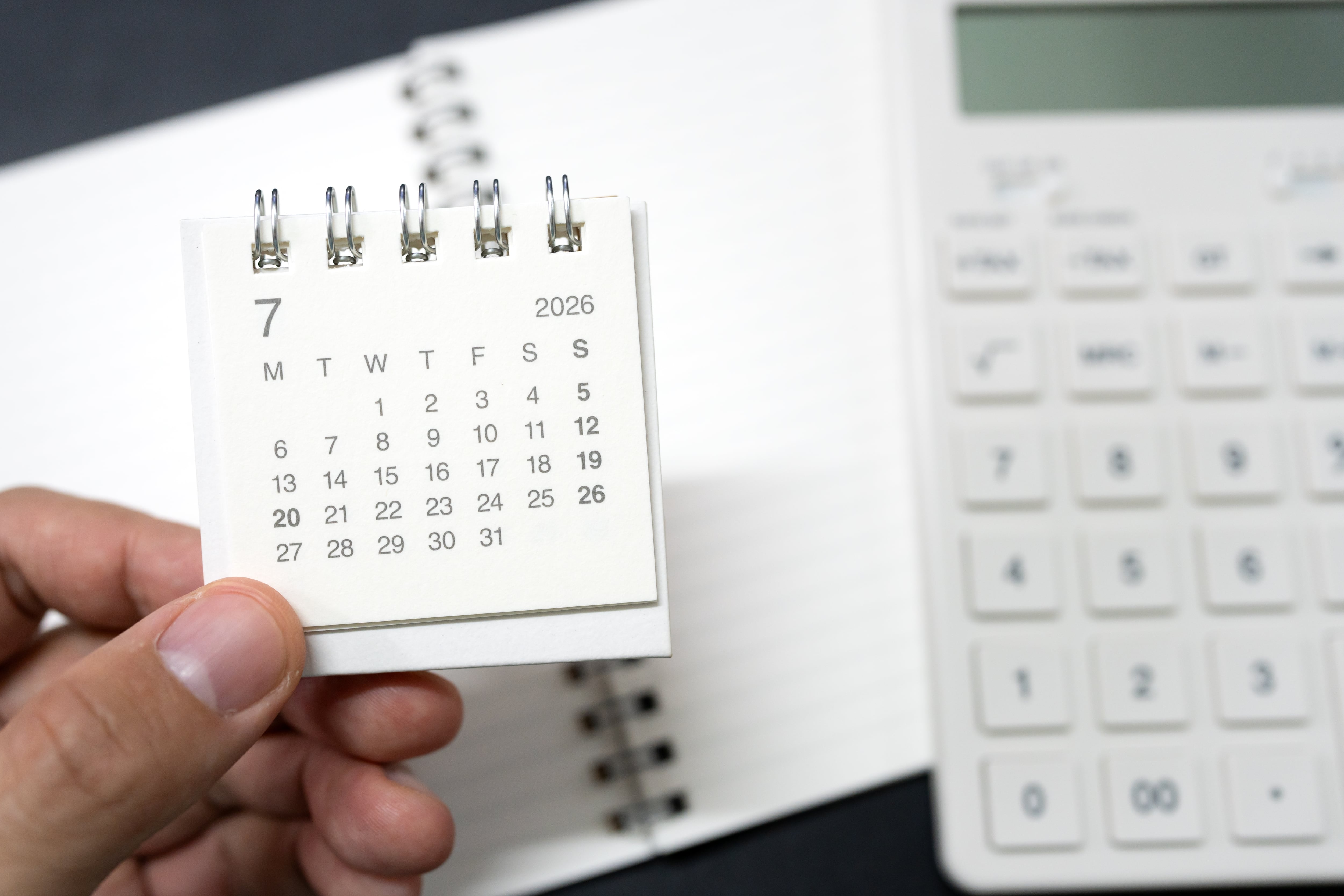 Persona revisando facturas y calculadora sobre una mesa con billetes y monedas