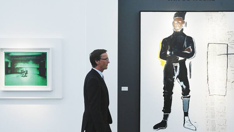 Un visitante de una galería de Londres entre una obra de Andy Warhol y otra de Jean-Michel Basquiat