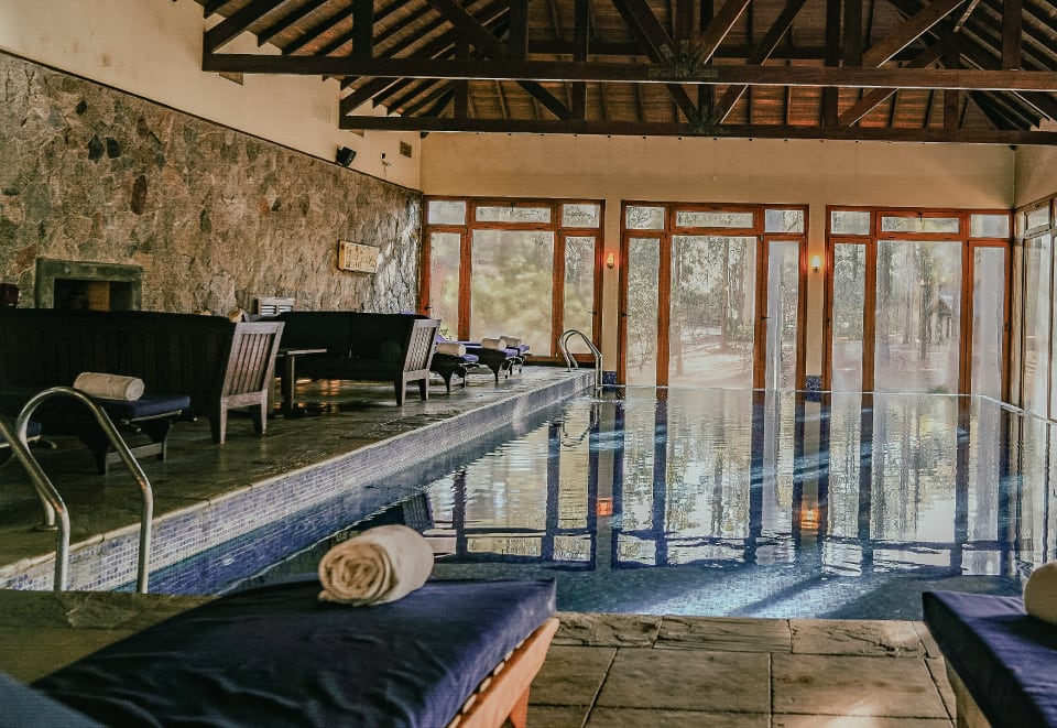 Piscina climatizada del Chandra Spa: pileta interior con grandes ventanales hacia los pinos y reposeras con toallas.