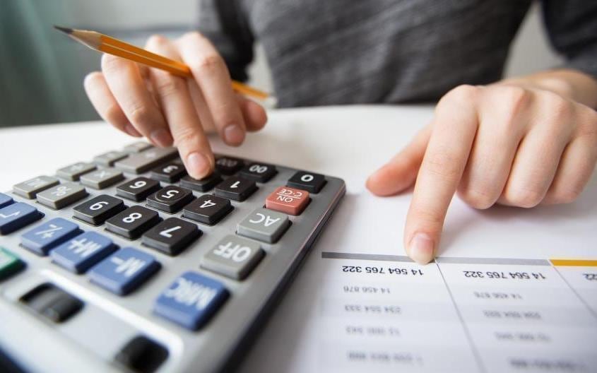 Documentos fiscales, calculadora y billetes sobre un escritorio con gráficos de impuestos