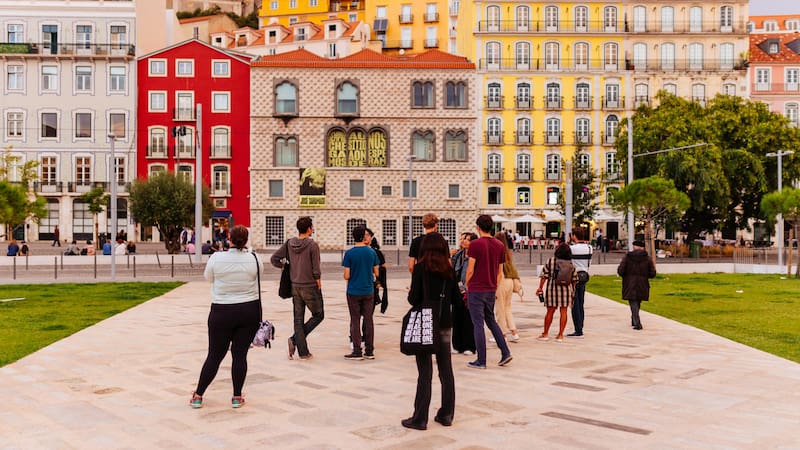 Personas pasean en el bello parque frente al centro histórico de Lisboa