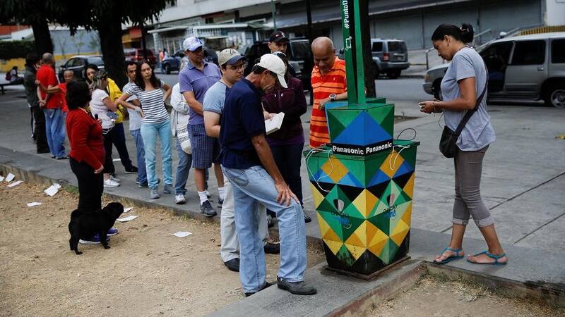 La gente se amontona para cargar sus celulares en los puestos de paneles de energía solar que hay en la calle.
