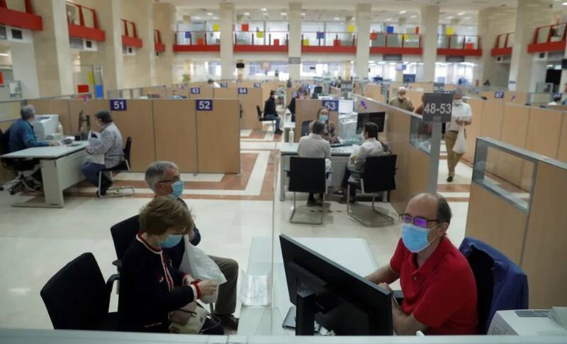 Varias personas son atendidas en la delegación de Hacienda de Guzmán el Bueno en Madrid (Foto: EFE/Emilio Naranjo).