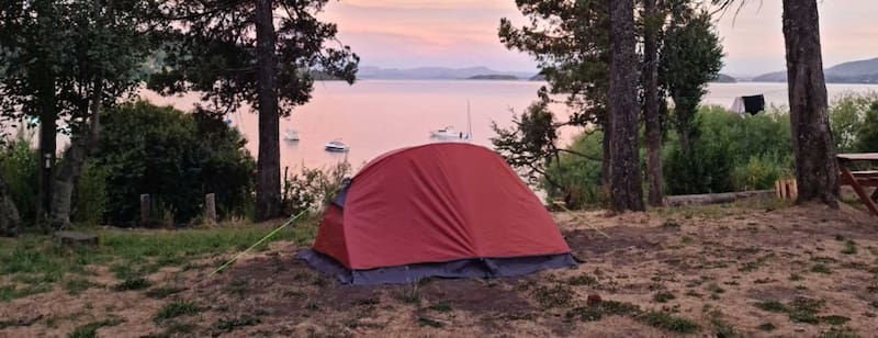 Vista desde la playa del Camping Petunia, con el Lago Nahuel Huapi y los cerros Catedral, López y Otto en el horizonte. (Foto: Web camping Petunia)