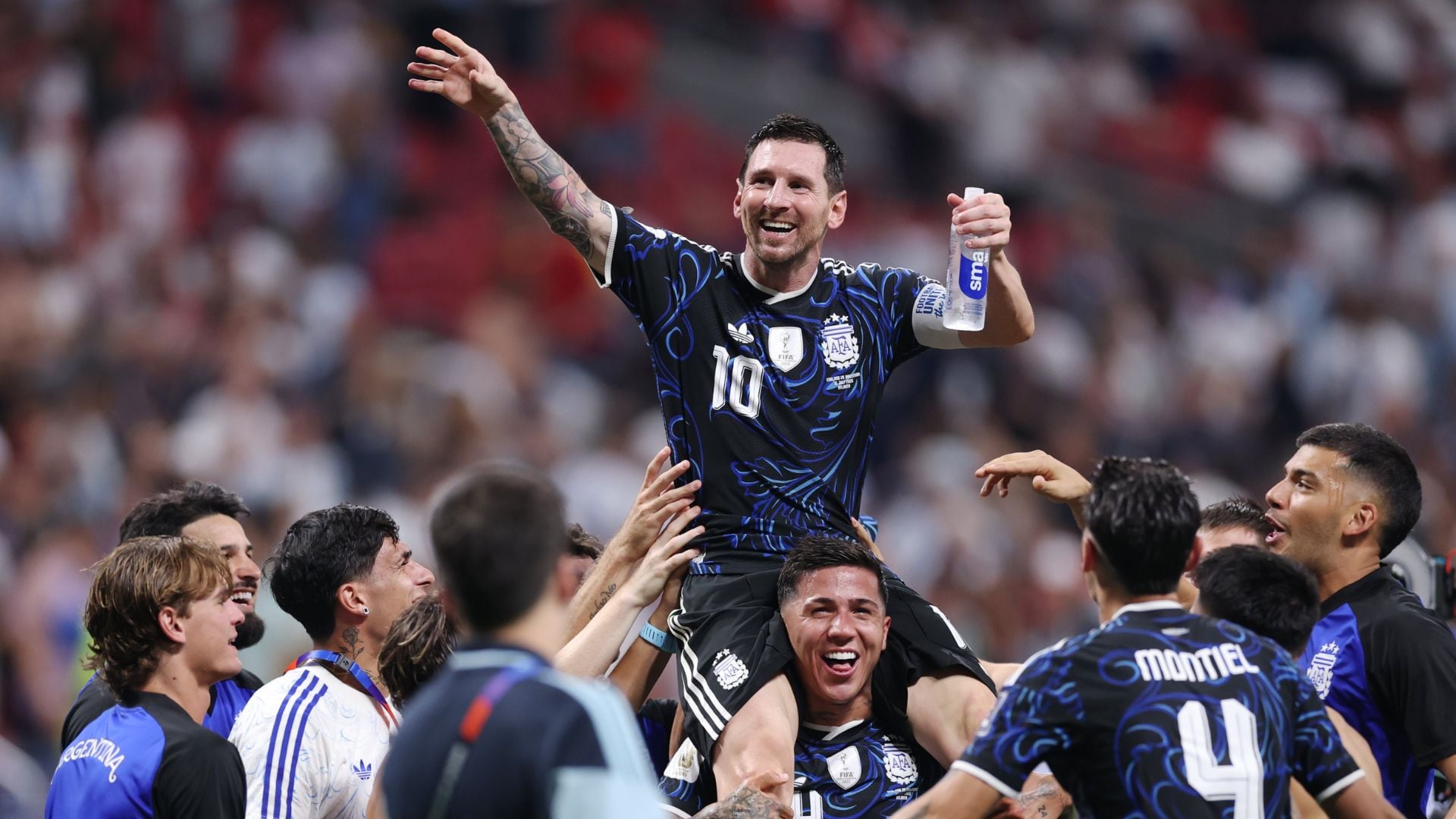 Jugadores de la Selección Argentina abrazados en el campo tras un partido, con la camiseta albiceleste