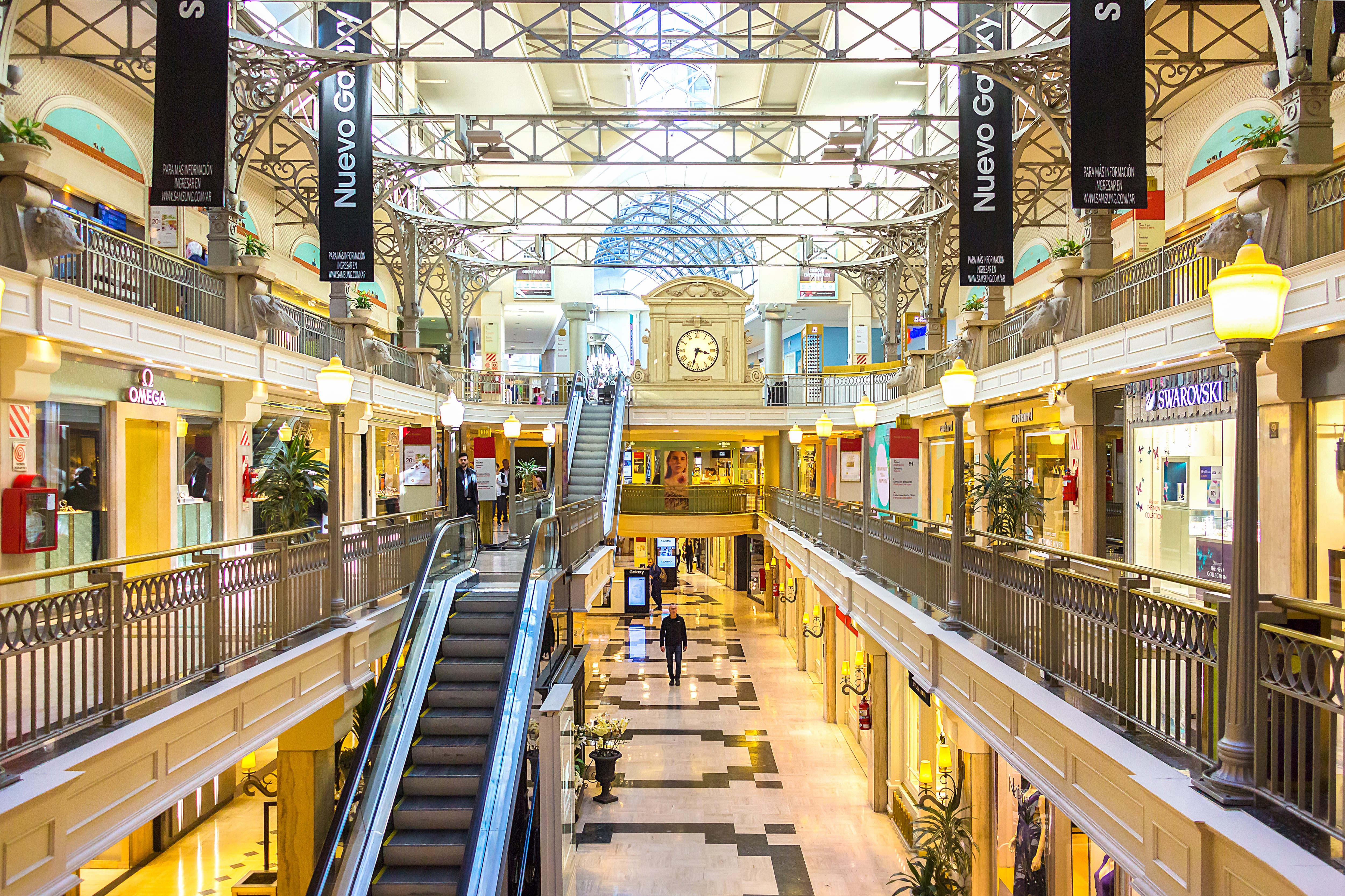 Fachada moderna del shopping Alto Palermo con vidrieras de lujo y clientes entrando