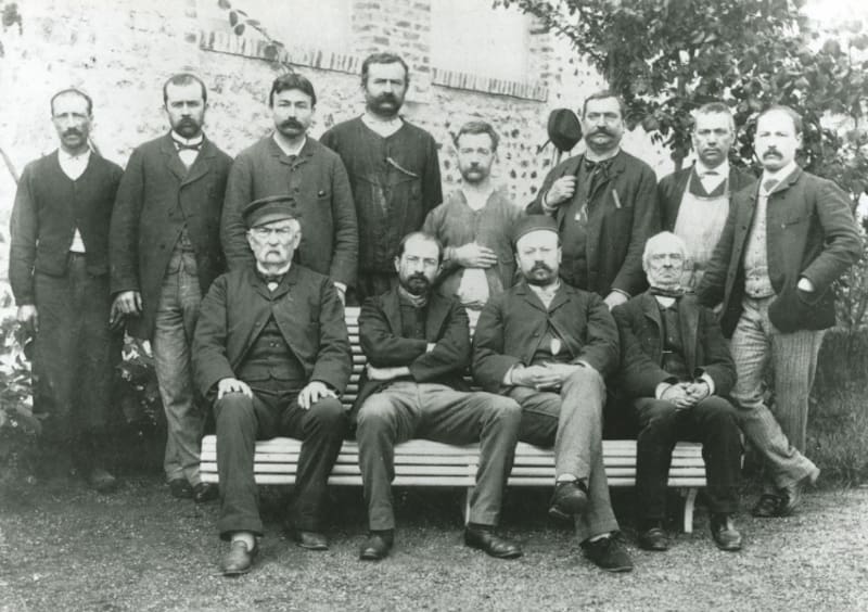 Édouard Michelin (sentado y de brazos cruzados) junto a los trabajadores de su fábrica.
