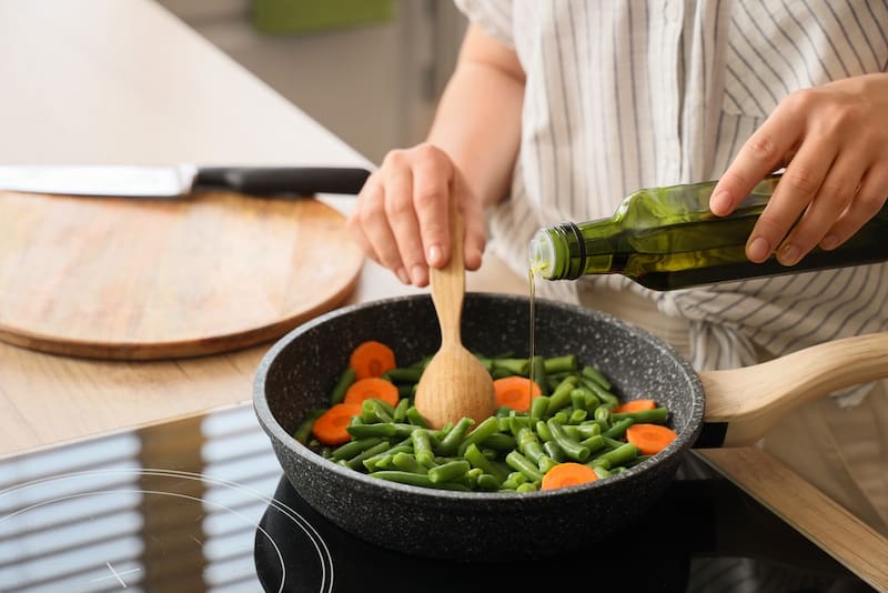 Persona prepara un alimento con aceite de oliva.