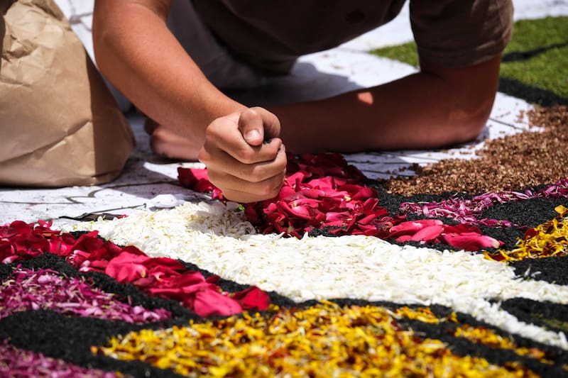 LA OROTAVA (TENERIFE), 11/06/2026.- Un grupo de personas confecciona este jueves las alfombras de flores para celebrar el Corpus Christi en el municipio tinerfeño de La Orotava, donde el magno tapiz principal ha tenido como motivo la visita del Papa Leon XIV, quien ha estado representado junto a un voluntario de Cruz Roja, una persona migrante y la Virgen del Carmen. EFE/Alberto Valdés