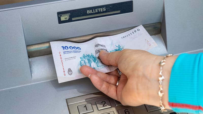 Argentina money. A woman takes out a 10,000-peso Argentine banknote from an ATM. Financial concept