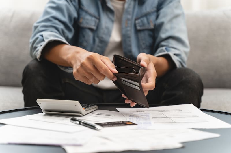 Concepto financiero del problema de la bancarrota, el hombre joven que abre la billetera vacía se estresa para encontrar dinero para pagar el período de la hipoteca de la deuda.