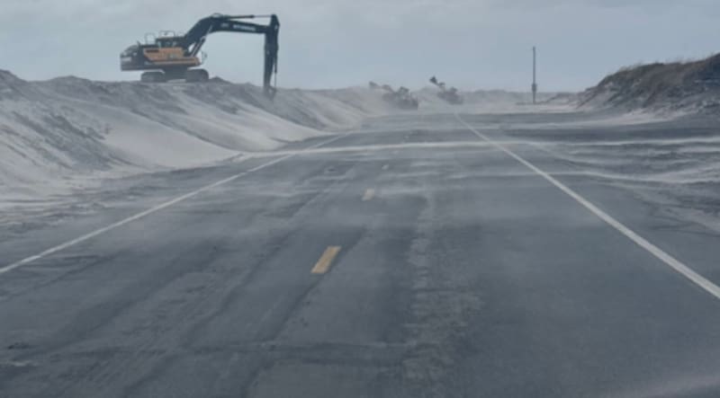 Una excavadora trabajando sobre las barreras de arena junto a la carretera NC-12, en Carolina del Norte.