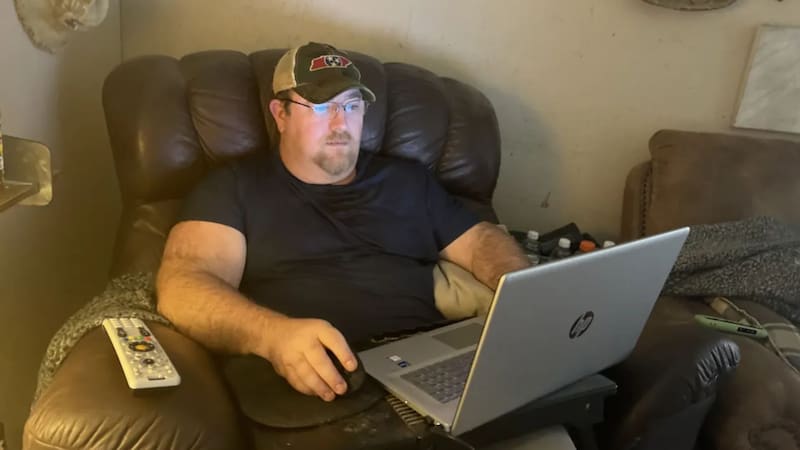 Chris Pyle sentado cómodamente en un sillón reclinable mientras trabaja concentrado en su computadora portátil apoyada sobre un soporte para regazo.