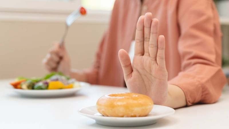 Mujer rechaza una dona para comer ensalada.
