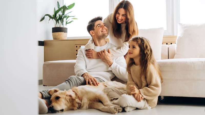 Smiling family spending quality time together with their golden retriever dog in the cozy living room, enjoying moments of happiness and love