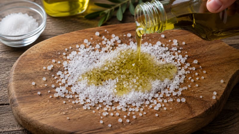 Para preparar esta mezcla, se deben espolvorear dos cucharadas de sal gruesa sobre la superficie de la tabla de madera y agregar una cucharada de aceite de oliva directamente sobre la sal.