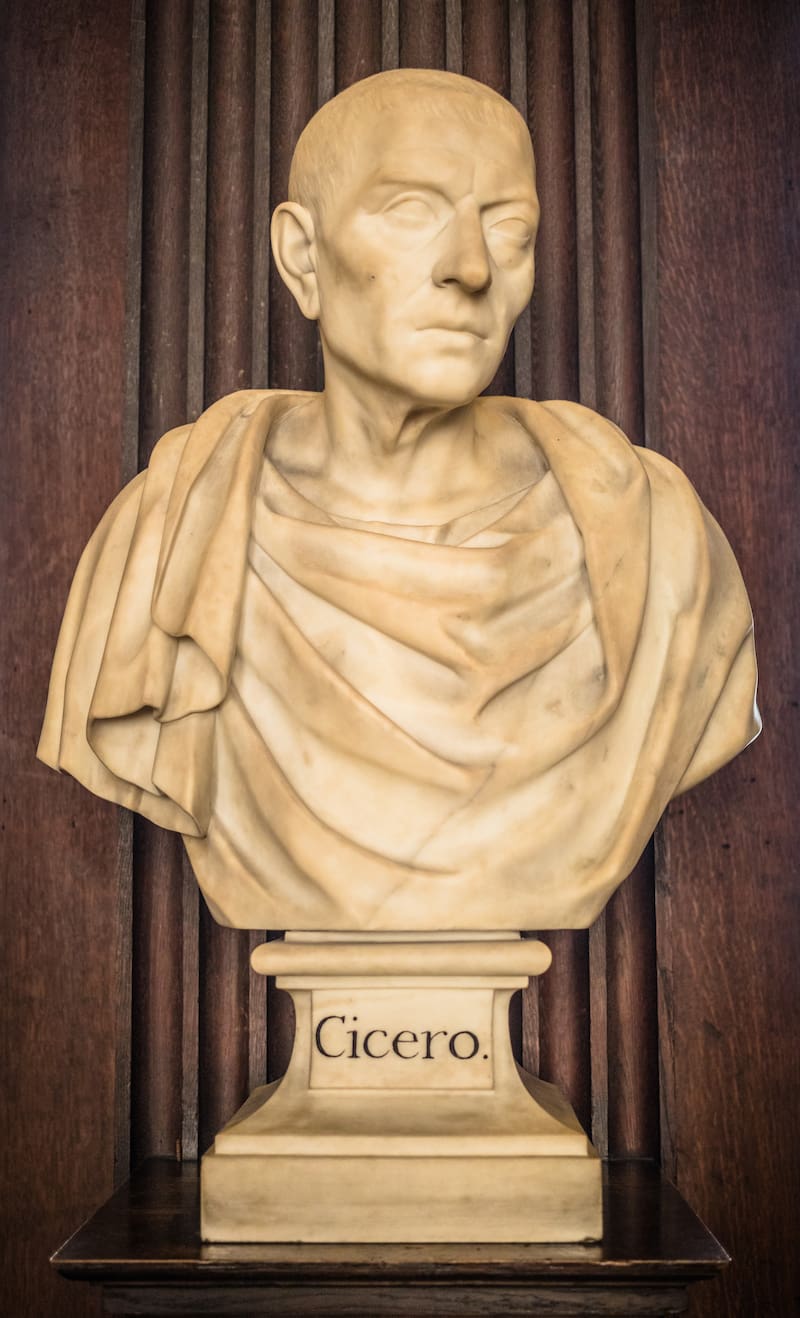 DUBLÍN, IRLANDA - 19 DE SEPTIEMBRE DE 2018: Busto de mármol de Cicerón en el interior de la Long Room de la Biblioteca del Trinity College, rodeado de estanterías históricas y esculturas clásicas.
