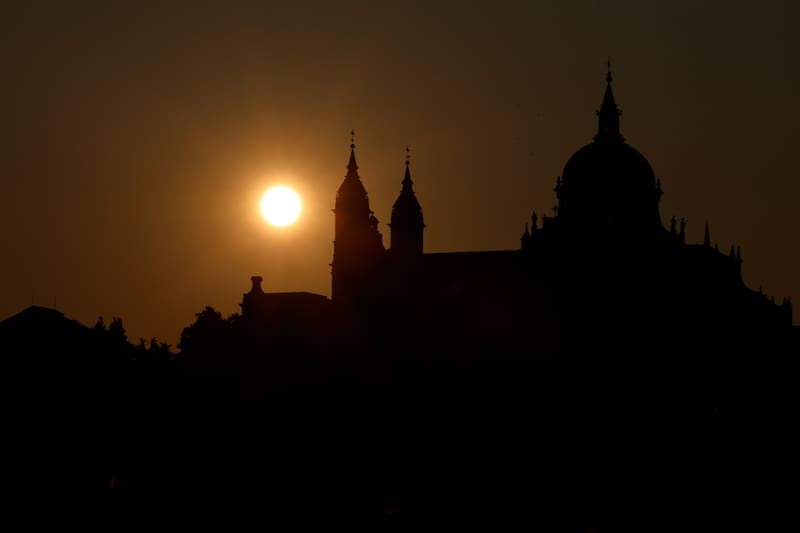 FOTODELDÍA MADRID, 26/07/2026.- La silueta de la Catedral de la Almudena se dibuja sobre el cielo de Madrid con las primeras luces de este domingo, en una jornada marcada por los graves incendios de la sierra oeste de Madrid y Ávila que siguen activos. La Agencia Estatal de Meteorología (Aemet) prevé hoy en la Comunidad de Madrid cielos poco nubosos o despejados. Además se esperan temperaturas mínimas en ligero descenso y máximas en aumento. Las mínimas oscilarán entre los 12 grados centígrados en Alcalá de Henares y los 17 en Madrid, mientras que las máximas llegarán a los 32 grados en Aranjuez y Navalcarnero y los 33 grados en Alcalá. EFE/Mariscal