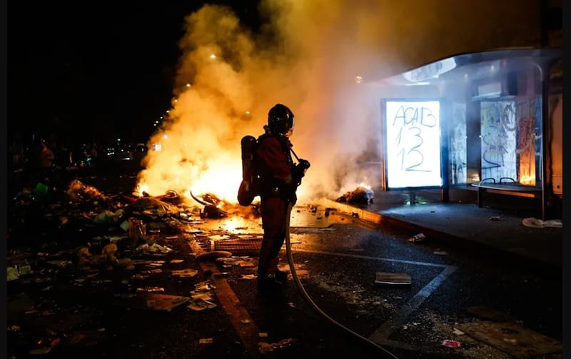 Un bombero francés trata de sofocar las llamas de una barricada en una calle de París.