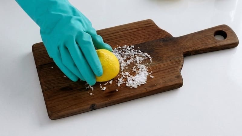 Frotar limón y sal gruesa en la tabla de madera.