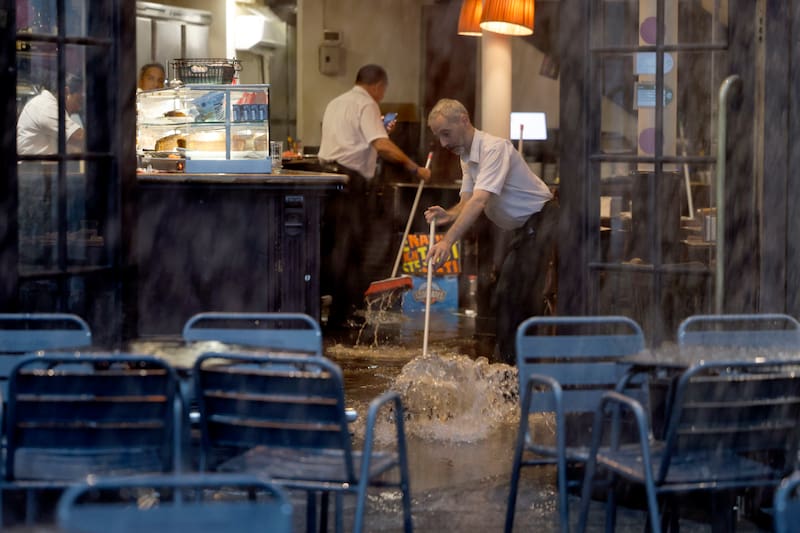 Empleados de una cafetería del centro de Barcelona achican agua del local este martes cuando Protección Civil ha hecho un llamamiento a tener "mucha prudencia".