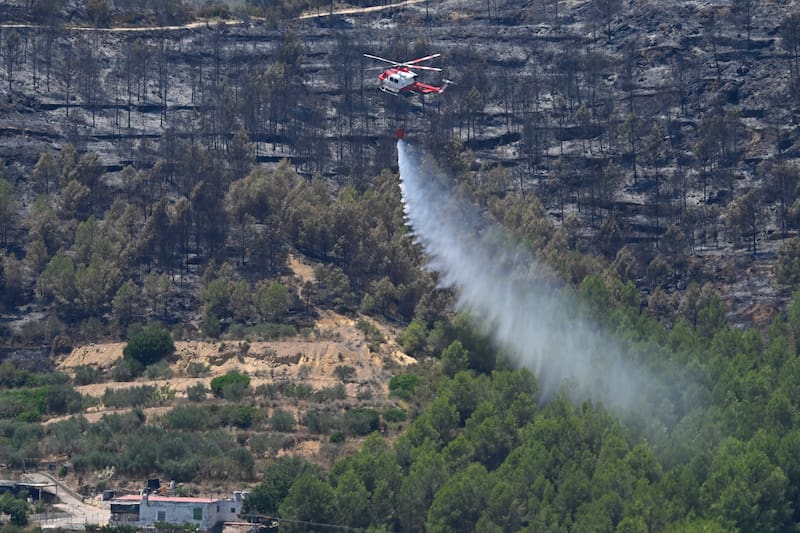 SONEJA (CASTELLÓN), 06/07/2026.- Un helicóptero de lucha contra el fuego recoge descaarga agua para la extinción del incendio forestal de Soneja (Castellón), que este domingo obligó al desalojo de 500 personas del vecino municipio de Azúebar. EFE/ Andreu Esteban