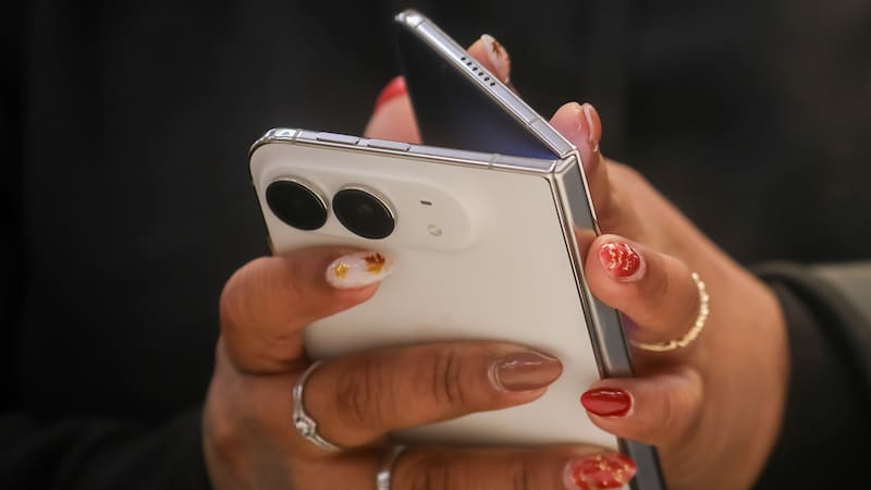 A customer holds an Apple iPhone Duo smartphone at Apple's Fifth Avenue store.