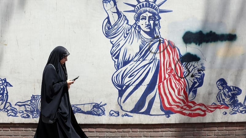 Una mujer pasa junto a un mural antiestadounidense cerca de la antigua embajada de EE. UU. en Teherán, Irán. Irán y EE. UU. intercambiaron disparos después de que el presidente estadounidense Trump declarara que el alto el fuego había terminado.