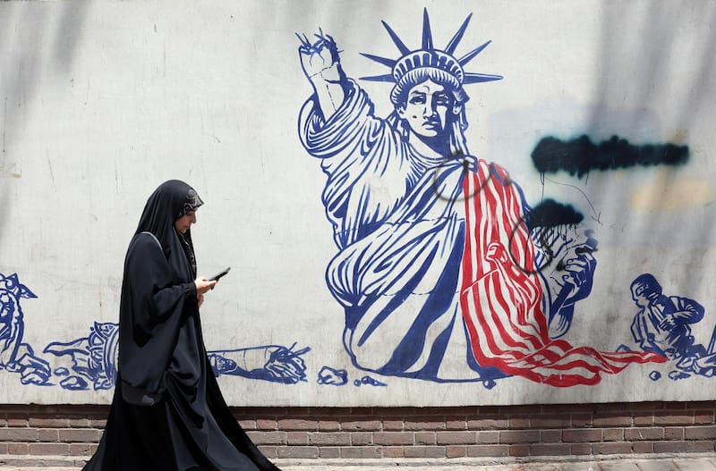 Una mujer pasa junto a un mural antiestadounidense cerca de la antigua embajada de EE. UU. en Teherán, Irán. Irán y EE. UU. intercambiaron disparos después de que el presidente estadounidense Trump declarara que el alto el fuego había terminado.