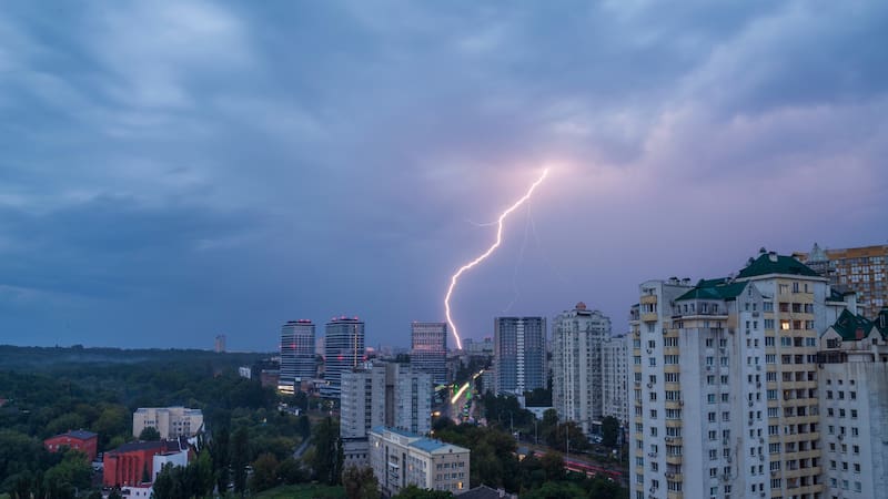 Kyiv, Ukraine, July 28, 2025. Against the backdrop of a cityscape with tall residential buildings, in a sky covered by thunderclouds, a bright lightning in a form flash of light appeared.