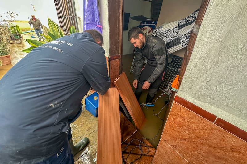 LORA DEL RÍO, 08/02/2026.-Varias personas intentan sacar el agua acumulada en sus viviendas de la localidad de Lora del Río tras las lluvias de los últimos días. La tregua que las lluvias han dado este domingo a Andalucía ha permitido el regreso a casa de algunas de las más de 11.000 personas evacuadas en los últimos días de sus viviendas por los efectos del tren de borrascas que asola la región y que aún no se puede dar por finalizado, pues las previsiones son que las precipitaciones regresen esta misma noche. EFE/ David Arjona