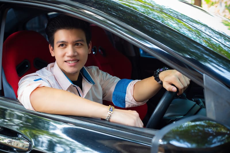 Portrait young handsome man sitting and smiling with happiness in a car