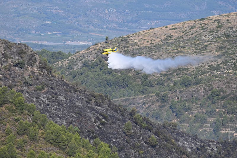 SONEJA (CASTELLÓN), 06/07/2026.- Una avioneta deja caer su carga para refrescar la zona afectada. Doce medios aéreos se han incorporado al amanecer a las labores de extinción del incendio forestal de Soneja (Castellón), que este domingo obligó al desalojo de 500 personas del vecino municipio de Azúebar y hasta el momento ha afectado a unas 150 hectáreas de superficie y a una pequeña parte del parque natural de la Sierra de Espadán. EFE/ Andreu Esteban