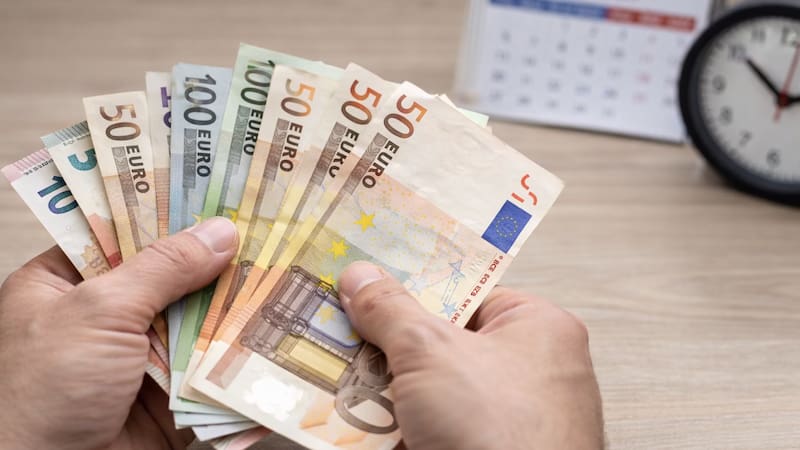 Manos contando billetes de euros en un entorno cotidiano, en el contexto de la suba del salario mínimo acordada por el Gobierno y los sindicatos.