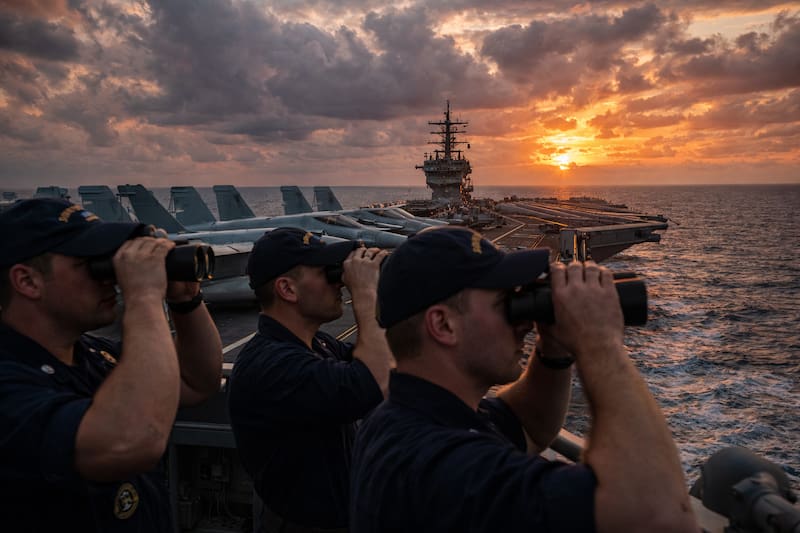Marineros estadounidenses vigilan el horizonte desde la cubierta de un portaaviones desplegado en el mar Arábigo. (Imagen generada con inteligencia artificial)