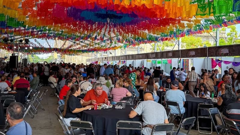Familias y asistentes reunidos disfrutando de la gastronomía bajo el tradicional papel picado en el Paseo Alcalde de Guadalajara.