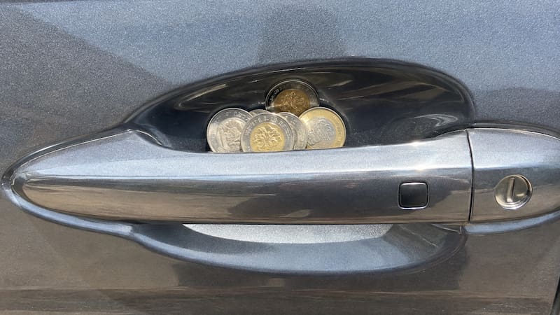 Colocar un conjunto de monedas en la manija del auto: para qué sirve y por qué lo recomiendan. (Representación creada con IA)