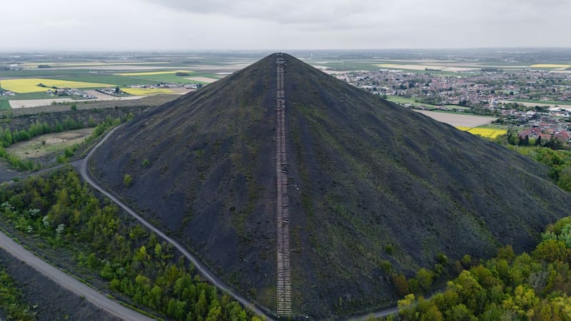 Vista en perspectiva de la pendiente de una de las gigantescas escombreras de carbón, atravesada en su centro por los rieles de una antigua vía de transporte.