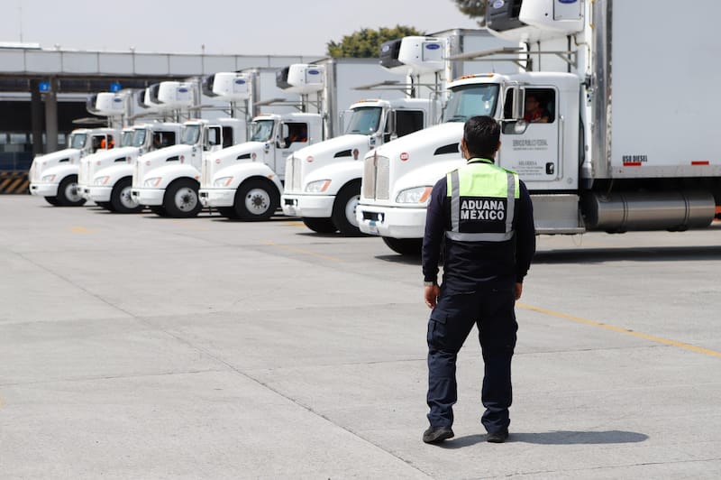 Trabajador de Aduanas México en un día de trabajo frente a camiones de carga.