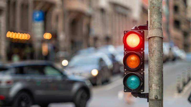 Paso por la ciudad con un semáforo sobre fondo borroso con autos en las calles de la noche, luz roja.
