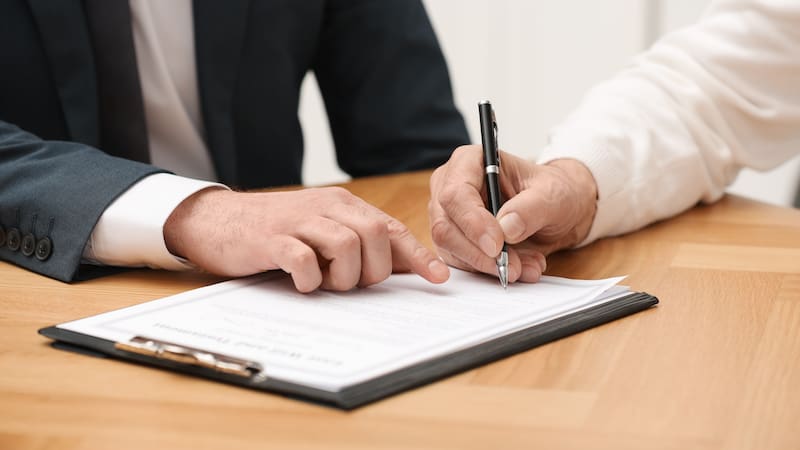 Imagen representativa de una persona firmando un testamento frente a su abogado.
