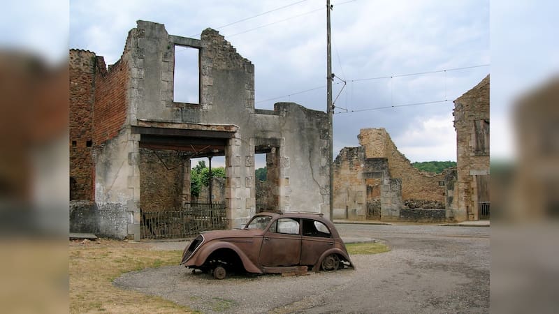 Peugeot 202 en estado ruinoso y algunos edificios en Oradour-sur-Glane. Fotografía del 25 de junio de 2006.