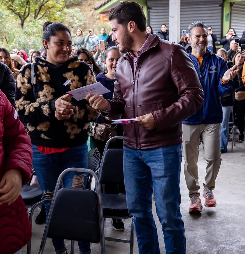 El Gobernador de Nuevo León, Samuel García, le entrega la tarjeta a mueres del programa Ayudamos a las Mujeres en Santiago.