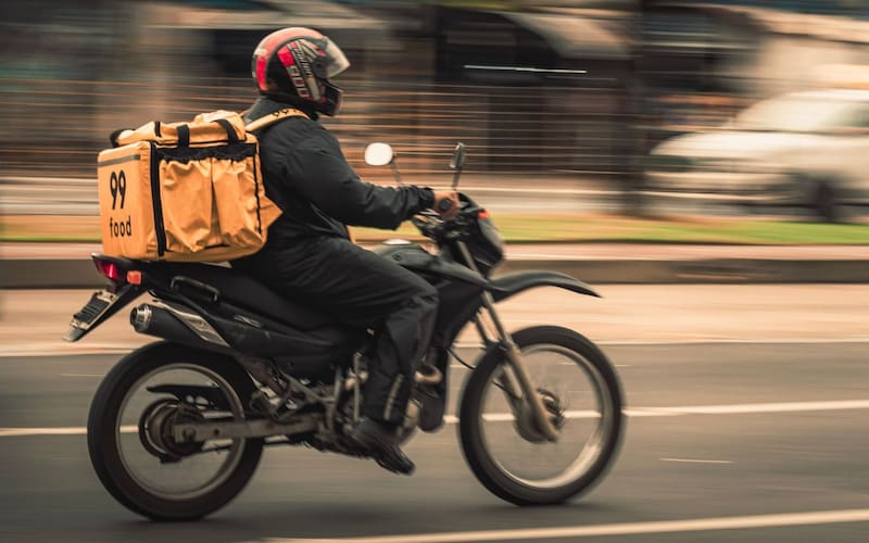 Image illustration. A food delivery worker rides through New York City. A new law will limit when delivery apps can deactivate workers' accounts.