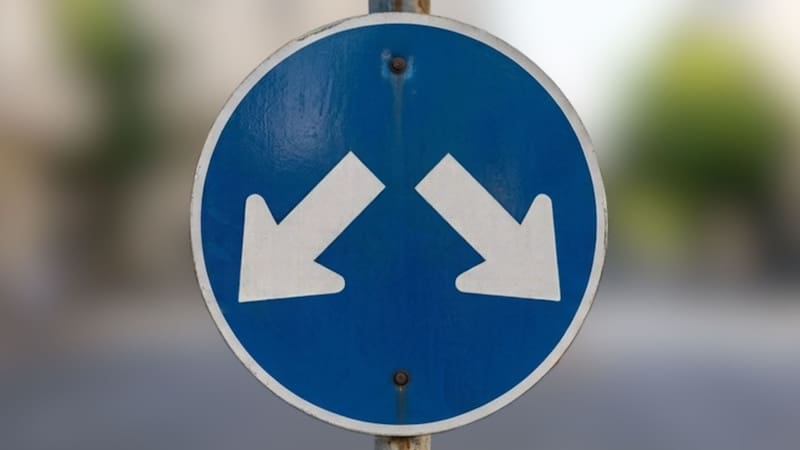Qué significa la señal de tránsito azul con dos flechas blancas hacia abajo y en distintas direcciones.